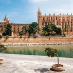 Couple of tourists looking at La Seu, the gothic medieval Cathedral of Palma de Mallorca and La Almudaina Royal Palace, Spain. The Cathedral of Santa Maria