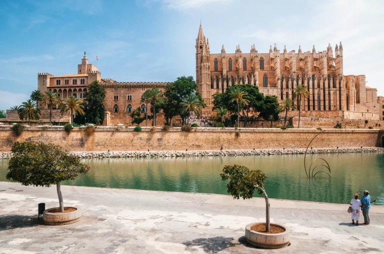 Couple of tourists looking at La Seu, the gothic medieval Cathedral of Palma de Mallorca and La Almudaina Royal Palace, Spain. The Cathedral of Santa Maria